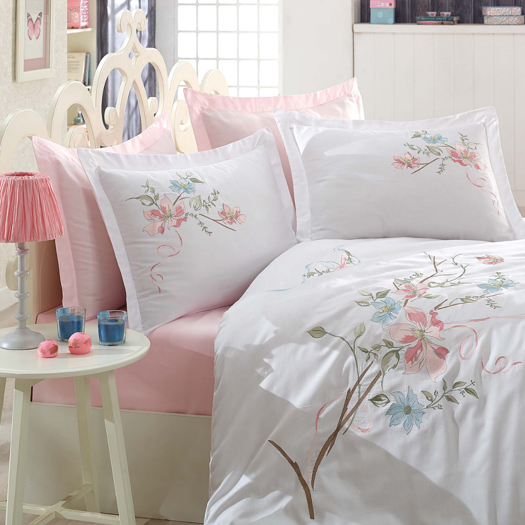 White master bed designed with pink bed sheet and white duvet cover having floral embroideries
