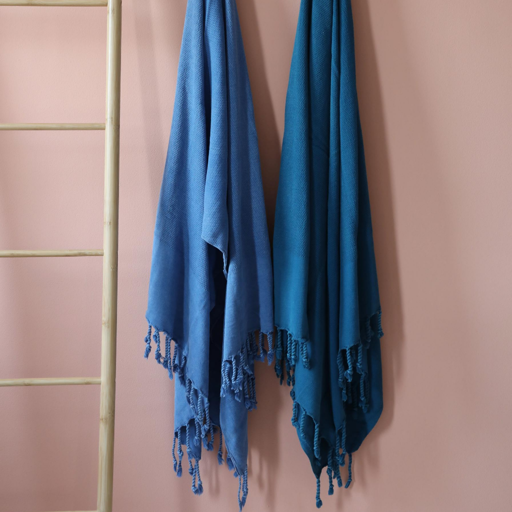 Two Turkish beach towels in marine-blue and petrol-blue colored hanging on a wall