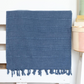Stone-washed, navy Turkish beach/bath towel on a bed frame
