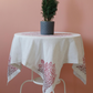 Linen table cloth has red, floral designs made by traditional hand printing